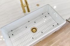 a white sink sitting on top of a wooden floor next to a faucet