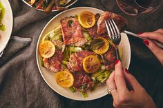 two plates of food on a table with utensils and wine glasses in the background