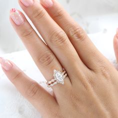 a woman's hand with a diamond ring on top of her finger and pink manicured nails