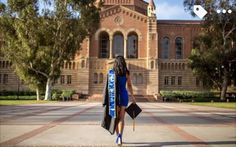 a woman walking in front of a building with a blue sash around her neck and holding an umbrella