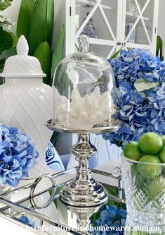 blue hydrangeas and limes in glass vases on a mirrored table