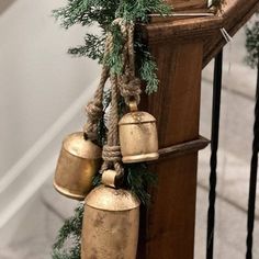 three bells hanging from the side of a wooden railing with pine branches on top and below