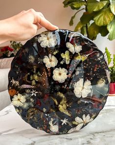 a person holding a black plate with white flowers on it