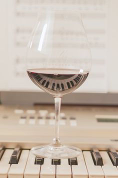 a glass of wine sitting on top of a piano keyboard