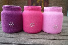 three pink and purple jars sitting on top of a wooden table