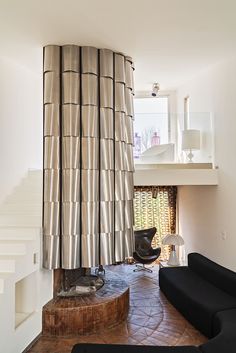 a living room with a black couch and some stairs in the backround area