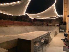 an empty skateboard park at night with lights strung over the top and below it