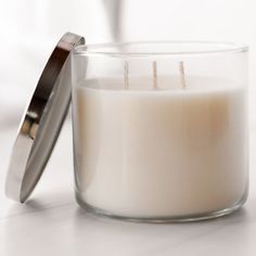 a white candle sitting on top of a table next to a metal container filled with candles