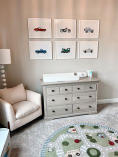 a baby's nursery room with cars on the wall and pictures above the dresser