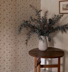 there is a vase with some plants in it on the table next to the wall