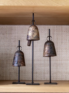 three metal bells are sitting on top of a shelf