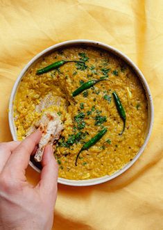 a person dipping some food into a bowl on top of a yellow table cloth,