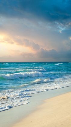 an ocean beach with waves coming in to shore and the sun peeking through the clouds