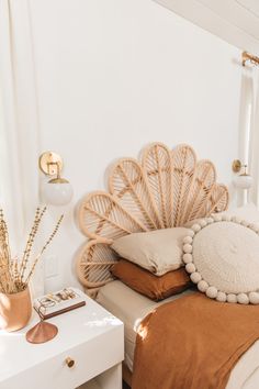 a white bed topped with lots of pillows next to a wall mounted clock and lamp