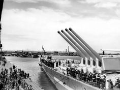 an old black and white photo of people on a boat in the water with large metal pipes sticking out of it's side