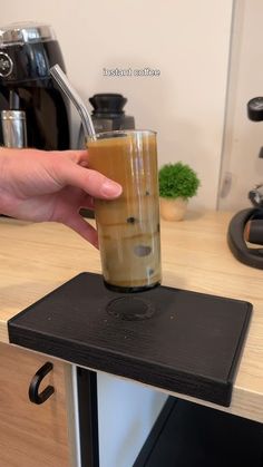 a person is holding a glass with liquid in it on top of a countertop