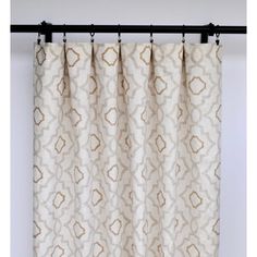 a curtain hanging on a black rod in front of a white and gold patterned curtain