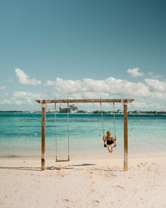 a woman sitting on a swing at the beach