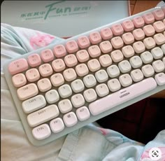 a white and pink keyboard sitting on top of a bed