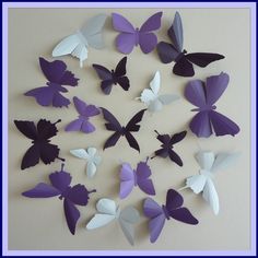 purple and white paper butterflies arranged in a circle on a wall with blue border around the edges