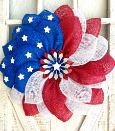 an american flag wreath with red, white and blue mesh flowers on the front door