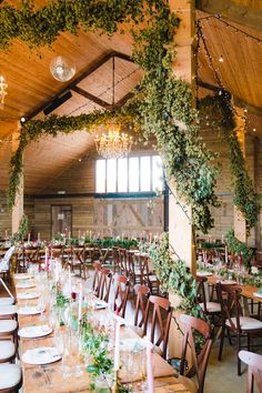 an indoor wedding venue with wooden tables and hanging greenery