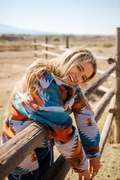 a woman leaning on a fence in the desert