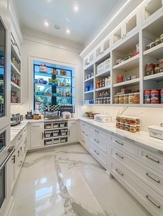 a large kitchen with white cabinets and marble flooring is shown in this image, there are many items on the shelves