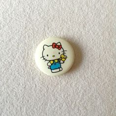 a hello kitty button with a bow on it's head sitting on a white surface