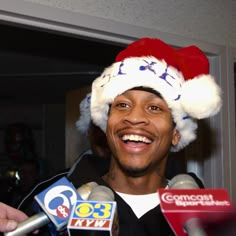 a man wearing a santa hat and surrounded by microphones