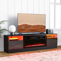 a flat screen tv sitting on top of a black entertainment center next to a potted plant