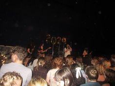 a group of people standing around each other in front of a stage with microphones