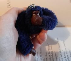 a hand holding a small toy gorilla keychain on top of an open book