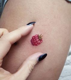 a woman's leg with a small tattoo on it and a raspberry