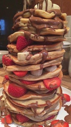 a stack of pancakes covered in chocolate and strawberries