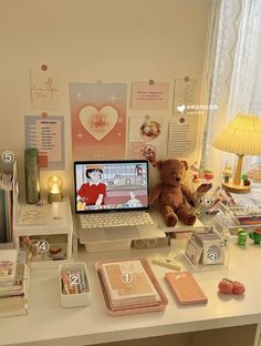 a laptop computer sitting on top of a desk next to a teddy bear and other items