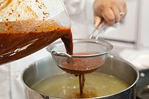 a person pouring something into a pot on the stove