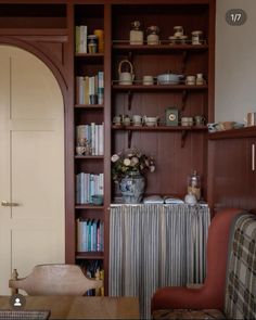 a living room filled with furniture and bookshelves next to a doorway in the wall