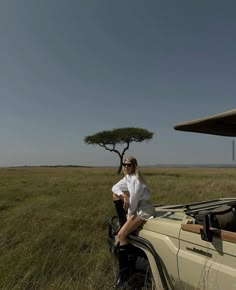 a woman sitting on the back of a safari vehicle