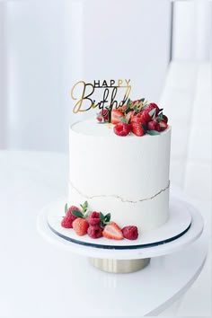 a white cake topped with strawberries and a happy birthday sign