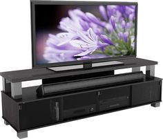 a flat screen tv sitting on top of a black entertainment center with purple flowers in the background