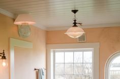 a bath room with a toilet a window and a light on the ceiling in it