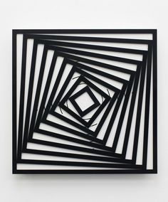 an abstract sculpture made out of black and white lines on a wall with one square in the center