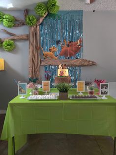 the lion king birthday party is set up with green tablecloths and desserts