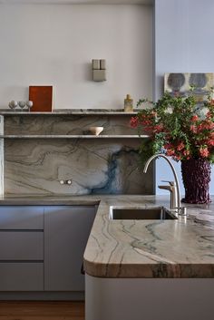 a kitchen with marble counter tops and stainless steel appliances in the center, along with a vase filled with flowers