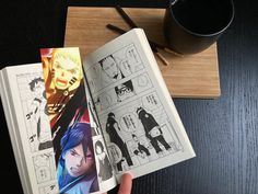 an open comic book on a table next to a cup of coffee