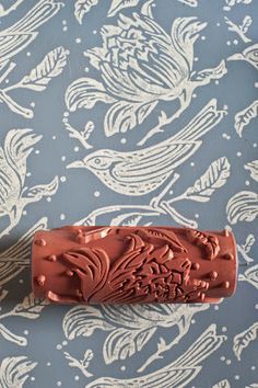 a red rubber stamp sitting on top of a blue and white wallpaper covered in birds