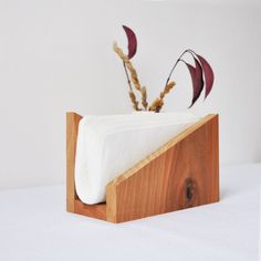 a tissue dispenser with some flowers in it on a white tablecloth