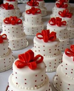 many small white cakes with red bows on them