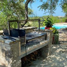 an outdoor bbq grill next to a swimming pool with trees in the foreground